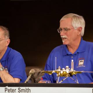 NASA Director Charles Elachi Discusses Phoenix Landing Caption: NASA Director Charles Elachi speaks at a press conference, using a microphone to discuss the Phoenix landing and pointing towards the space shuttle at the table in front of him, while another man listens attentively.