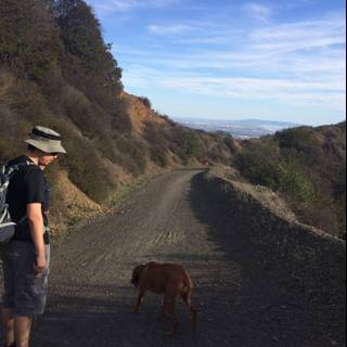 Man and Dog Enjoying a Walk on a Dirt Road