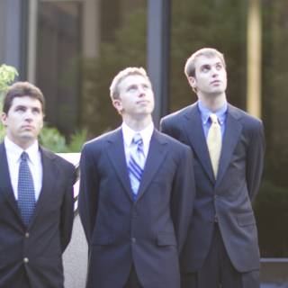 Three Men in Suits Pose in Front of Building