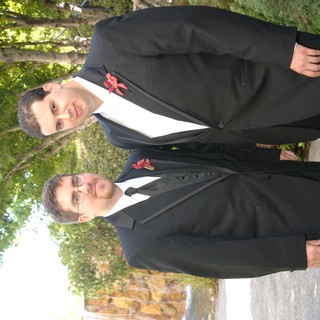 Two Groomsmen Posed in Black Tuxedos Outdoors