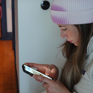 Young Woman Using Smartphone in White Puffy Jacket