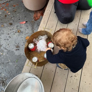 Child Reaching for Ice in Golden Beverage Tub