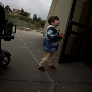 Young Boy Looking Up at Bus on Overcast Day