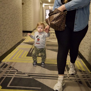 Toddler and Mother Walking Through Hotel Corridor
