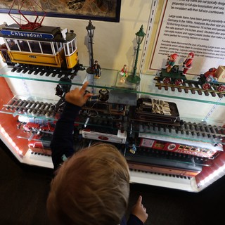 Child Exploring Vintage Train Models at Museum Display