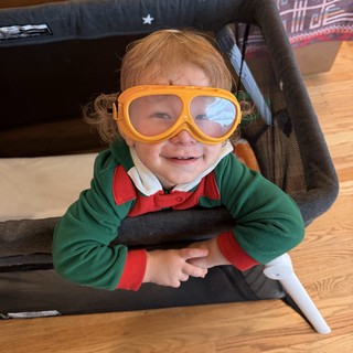 Cheerful Child in Orange Goggles and Green Jacket