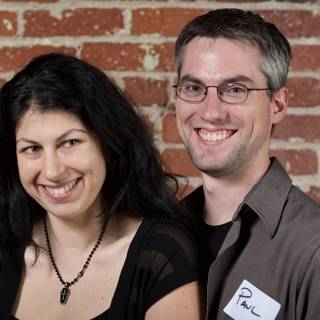 Smiling Couple Poses in Front of Textured Brick Wall