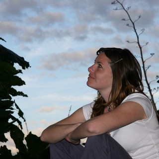 Woman Gazing Upward at Dusk Amid Tropical Foliage