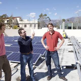 Three Men Working on Solar Panels on Rooftop
