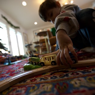 Child Playing with Wooden Train Set at Home
