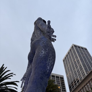 Towering Goddess Statue Against Urban Skyline