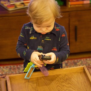 Toddler Playing with Toy Cars on Wooden Tray