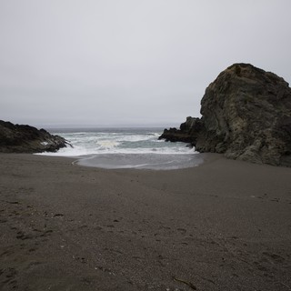 Rugged Cove Where Waves Meet Dark Sand