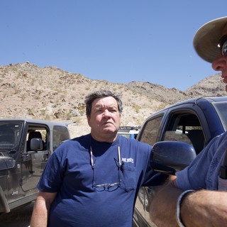 Two Men Conversing Beside Jeeps in Desert Terrain