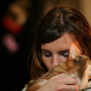 Tender Moment: Woman Embracing Ginger Kitten Lovingly