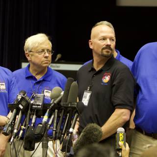 Press Conference with Four Men in Blue Shirts