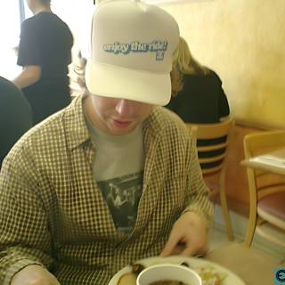 Man in a Baseball Cap Enjoying a Meal at a Downtown Cafe