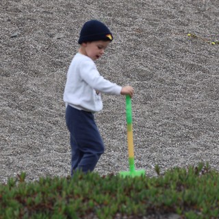 Young Boy Playing with Shovel on Sandy Beach