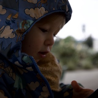 Child in Dinosaur Hood Enjoying Outdoor Meal