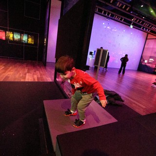 Child Exploring Interactive Museum Exhibit in Purple Light