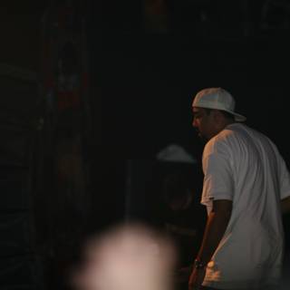 Man in White Shirt and Baseball Cap on Stage