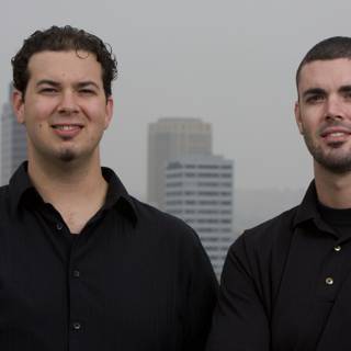 Two Happy Men in Black Shirts at a City Skyscraper