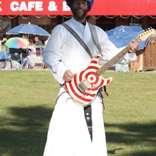 Man in White Robe Playing the Guitar Outdoors
