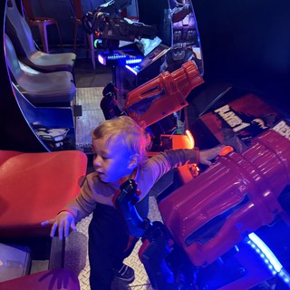 Child Playing Retro Arcade Games in Blue-Lit Gaming Pod