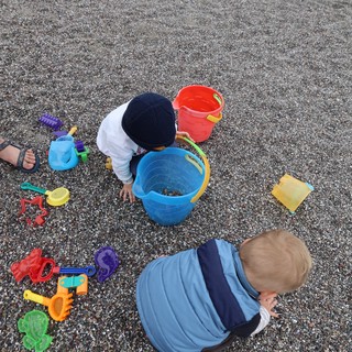 Toddlers Exploring Pebble Beach with Colorful Toys