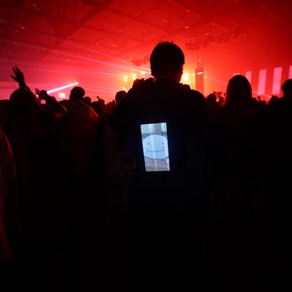 LED Backpack Glows Amid Red-Lit Festival Crowd