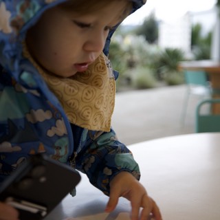 Young Child Examining Food at Outdoor Restaurant