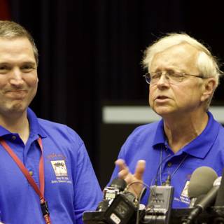 Press Conference with Two Men in Blue Shirts