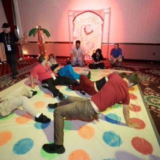 Giant game night with family and friends Caption: A group of people, including children and adults, gather together in a living room to play on a giant game. The flooring and footwear are visible, along with various clothing and accessories.