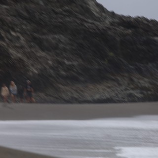 Figures Walking Along Rocky Coastal Beach