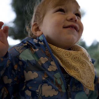 Joyful Toddler in Airplane Print Jacket Looking Up