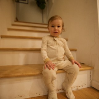 Toddler in White Pajamas Sitting on Wooden Stairs