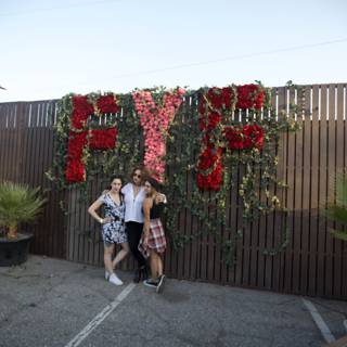 Three Women Posing in Front of a Flower Wall