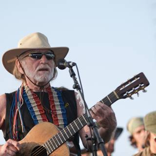 Willie Nelson Rocks the Okeechobee Music and Arts Festival Caption: Country legend Willie Nelson takes the stage in his signature cowboy hat and sunglasses, strumming his guitar and singing for the ecstatic crowd at the 2007 Okeechobee Music and Arts Festival.