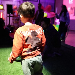 Child Dancing at Purple-Lit Baby Rave Event