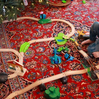 Child Playing with Wooden Train Set Under Christmas Tree
