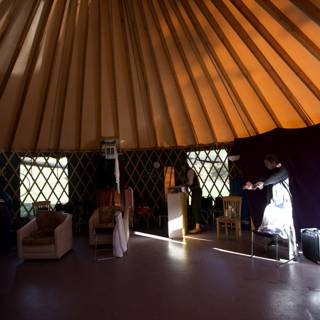 Center Stage in the Yurt Caption: A solo performer commands attention in the cozy yurt setting, surrounded by warm lighting and rustic furniture.