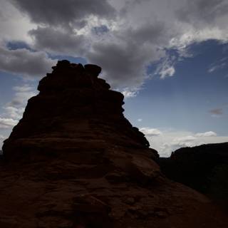Silhouetted Rock Formation against a Captivating Cloudy Sky