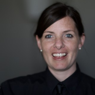 Smiling Woman in Black Against Grey Background