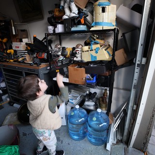 Toddler Exploring Cluttered Garage Workshop Storage