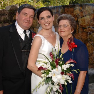 Bride Poses with Parents at Waterfall Wedding Venue