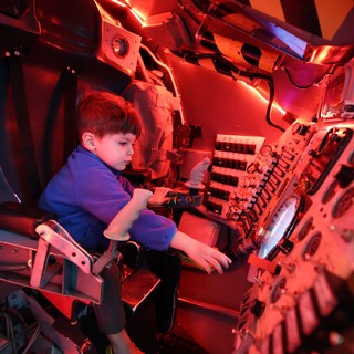 Young Explorer in Submarine Control Room Under Red Light