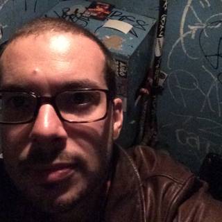 Self-portrait of a Man with Glasses and Brown Jacket in Graffiti-Filled Bathroom