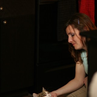 Woman Tenderly Petting a Kitten in Dim Light