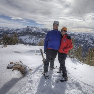 Summit Smiles: Couple Atop Snow-Covered Mountain Peak