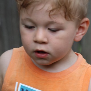 Young Child in Orange Tank Top Looking Down